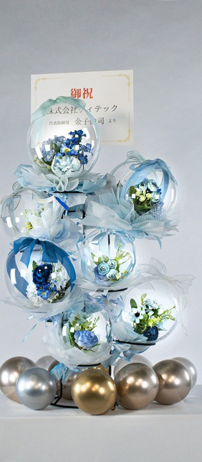 複数のバルーンに花が封入されたプレゼント仕様の祝い花。青を基調としたデザインで豪華な印象